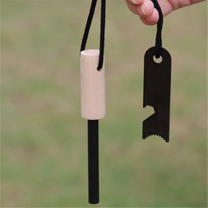 Fire starter with wooden handle and black metal striker on a blurred green background. ferro rod