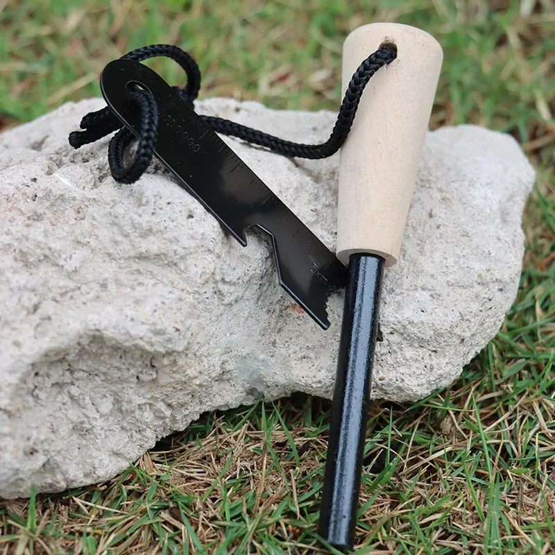 Fire starter tool with wooden handle and black metal head on a rock