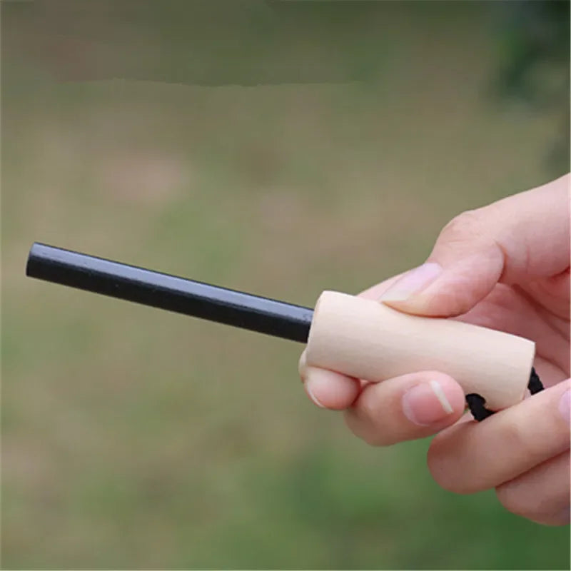 Hand holding a black fire starter against a blurred green background